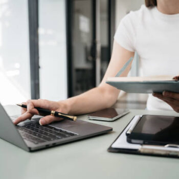 Female businessman use a smartphone and take notes in the notebook at the office desk in the morning.